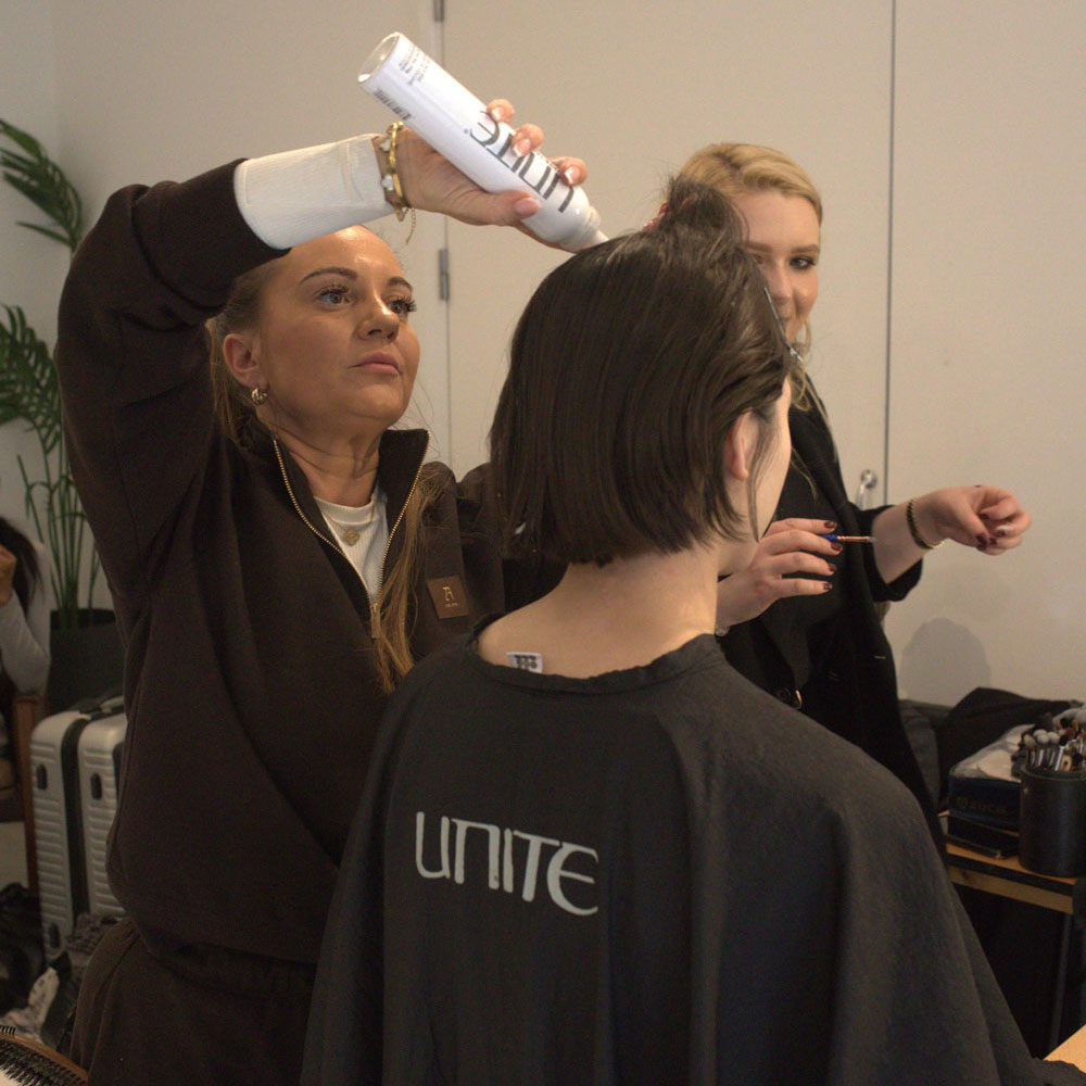 Coiffeuse backstage stylisant un carr&eacute; court pour un look de d&eacute;fil&eacute;.